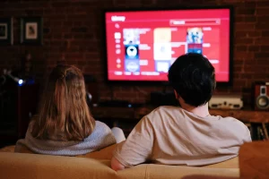 Bild på ett par som sitter i soffan och streamer en serie.
